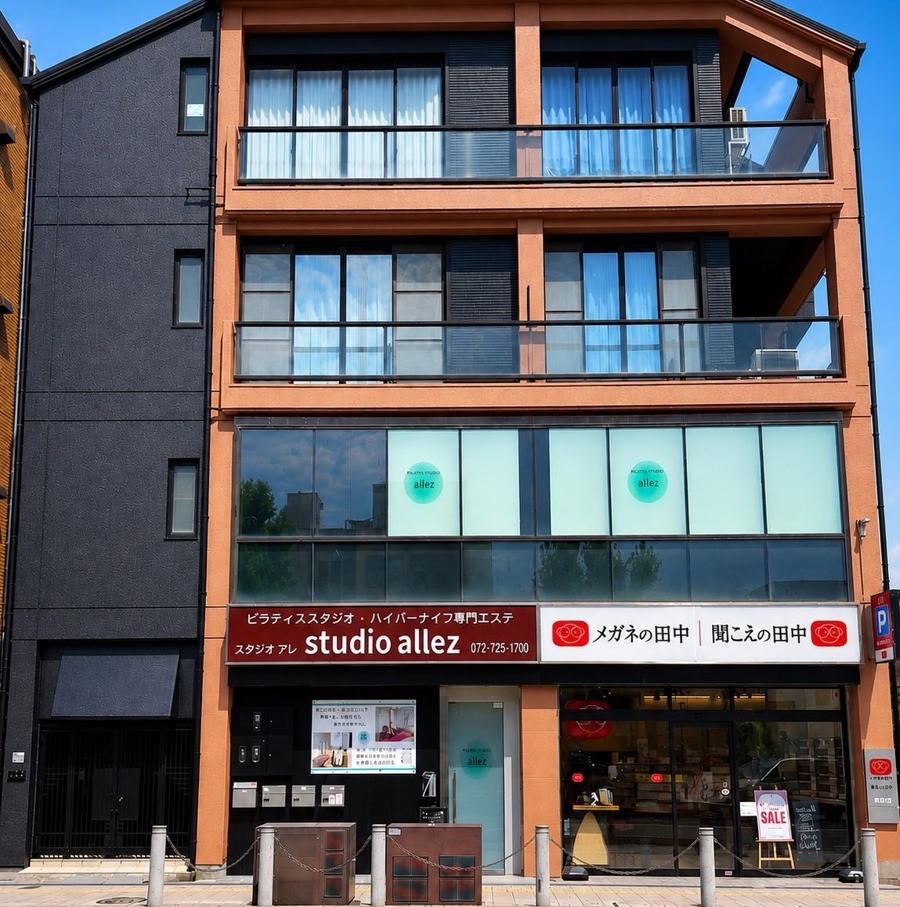studio allez の外観。オレンジ色のビル、えんじ色の studio allez 看板が目印